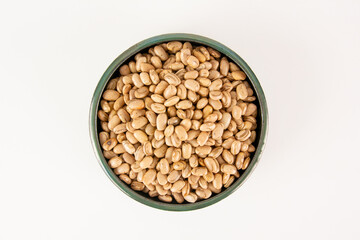Prato de feijao cru servido em uma tigela de barro em um fundo branco em vista aerea