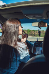 A girl sits in a car and paints her lips.