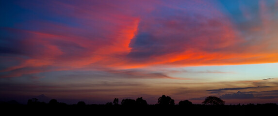 Panorama Sunlight with dramatic sky on dark background.Vivid sky on dark cloud.Red cloud sky.