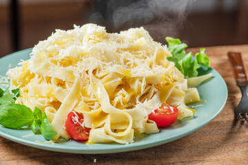 Hot, steaming freshly prepared pasta dish and fresh vegetables near it, Pasta is mediterranean Italian traditional cuisine.