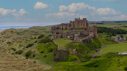 Aerial Bamburgh Castle. Bamburgh Castle, on the northeast coast of England, by the village of Bamburgh in Northumberland, is a Grade I listed building.

