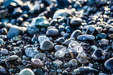 Almost as silver jewelry. Ice imaginarium. Icy particles and pieces on the black wet volcanic pebbles beach called Diamond Beach. Eastern Iceland, Europe