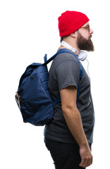 Young hipster man wearing red wool cap and backpack over isolated background looking to side, relax profile pose with natural face with confident smile.