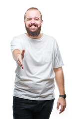 Obraz premium Young caucasian hipster man wearing casual t-shirt over isolated background smiling friendly offering handshake as greeting and welcoming. Successful business.
