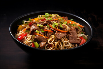 Chinese noodles with beef and vegetables in a bowl on a dark background
