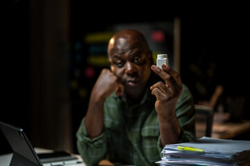 A man is holding a pill bottle in his hand while sitting at a desk