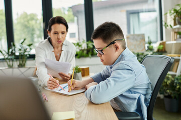 A mother works at her desk while her son colors nearby, both with focused expressions, showing an...