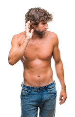 Handsome hispanic model man sexy and shirtless over isolated background smiling with hand over ear listening an hearing to rumor or gossip. Deafness concept.