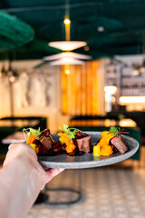 Close-up of gourmet food on a plate, featuring diced meat and colorful garnishes in a restaurant setting