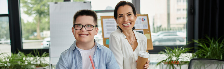 A mother and her son with Down syndrome happily working together in an office setting.