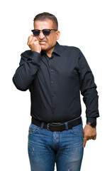 Middle age arab man wearing sunglasses over isolated background looking stressed and nervous with hands on mouth biting nails. Anxiety problem.