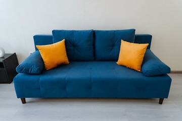 The living room feels cozy with a chic azure couch and vivid orange pillows creating a warm and...