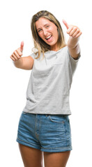 Young beautiful woman over isolated background approving doing positive gesture with hand, thumbs up smiling and happy for success. Looking at the camera, winner gesture.