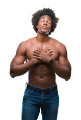 Fototapeta premium Afro american shirtless man showing nude body over isolated background smiling with hands on chest with closed eyes and grateful gesture on face. Health concept.
