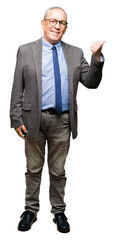 Handsome senior businesss man wearing glasses and tie smiling with happy face looking and pointing to the side with thumb up.