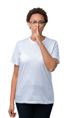 Beautiful young african american woman wearing glasses over isolated background asking to be quiet with finger on lips. Silence and secret concept.