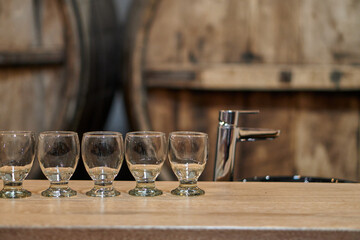 empty glasses inside a wine cellar with barrels in the background waiting for a wine tasting tour in Cafayate, Salta, Argentina.