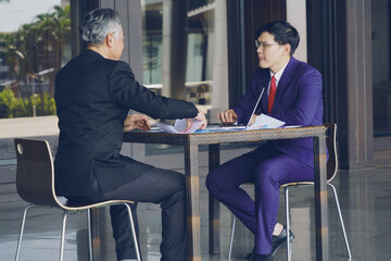 Businessman in a suit sitting talking, giving a presentation, inspecting work with a tablet, meeting with a supervisor, senior boss shaking hands after a company meeting.
