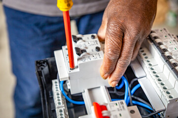 Close-up hand of a electrician working with a screwdriver on a industrial panel mounting and assembling new wiring on breakers.