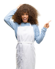 African american shop owner woman wearing an apron pointing away side with finger