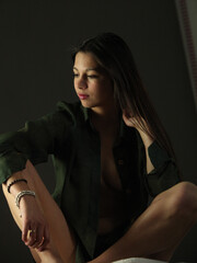 young sexy woman in unbuttoned green shirt   and long dark hair in low lighting 