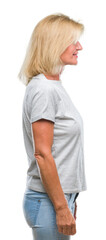 Fototapeta premium Middle age blonde woman over isolated background looking to side, relax profile pose with natural face with confident smile.