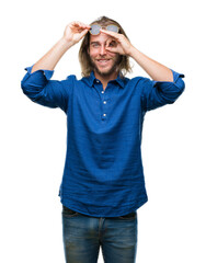 Naklejka premium Young handsome man with long hair wearing sunglasses over isolated background doing ok gesture with hand smiling, eye looking through fingers with happy face.