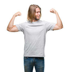 Young handsome man with long hair over isolated background showing arms muscles smiling proud. Fitness concept.