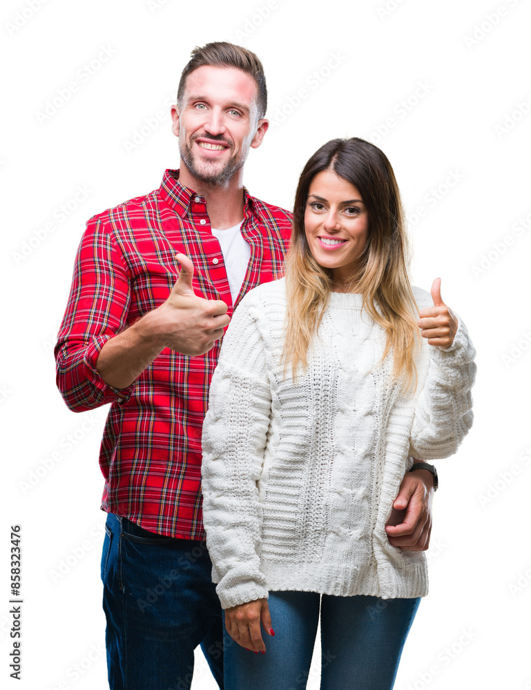 Canvas Prints Young couple in love wearing winter sweater over isolated background doing happy thumbs up gesture with hand. Approving expression looking at the camera with showing success.