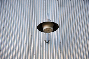 Outside lamp on an industrial corrugated metal wall