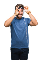 Fototapeta premium Young handsome man wearing headphones listening to music over isolated background doing ok gesture with hand smiling, eye looking through fingers with happy face.
