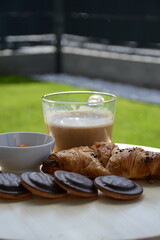 Delicious fresh sweet breakfast croissant with jam marmalade and coffee outside on patio garden
