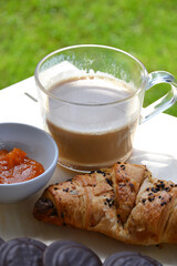 Delicious fresh sweet breakfast croissant with jam marmalade and coffee outside on patio garden