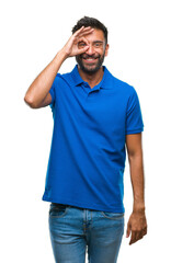 Fototapeta premium Adult hispanic man over isolated background doing ok gesture with hand smiling, eye looking through fingers with happy face.