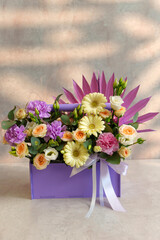 Assorted flowers arranged neatly inside a charming purple box, ready to bring joy and cheer to someone special. Vertical photo