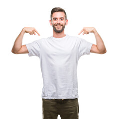 Naklejka premium Young handsome man over isolated background looking confident with smile on face, pointing oneself with fingers proud and happy.