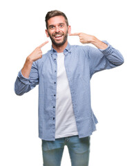 Young handsome man wearing white t-shirt over isolated background smiling confident showing and pointing with fingers teeth and mouth. Health concept.