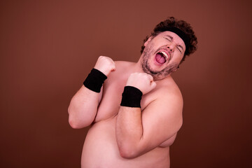 Fitness and healthy lifestyle. A funny fat man is doing sports. Brown background.