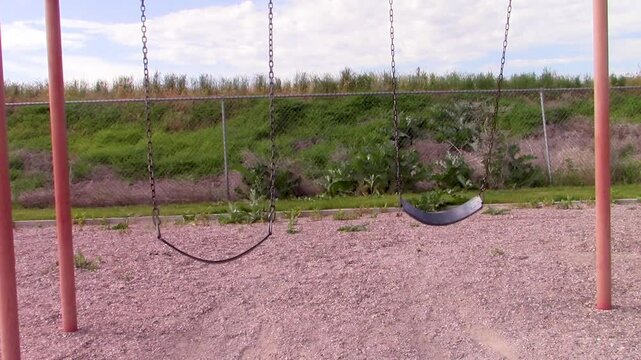 Front view of two rubber belt style swings that are swinging in opposite directions