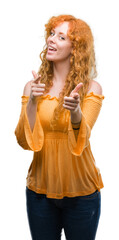 Young redhead woman pointing fingers to camera with happy and funny face. Good energy and vibes.