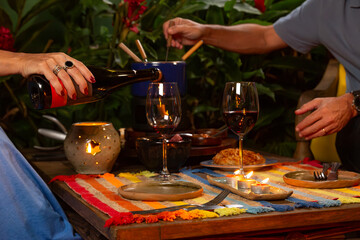 casal desfrutando de fondue e vinho tinto em um jantar a luz de velas em ambiente aconchegante.