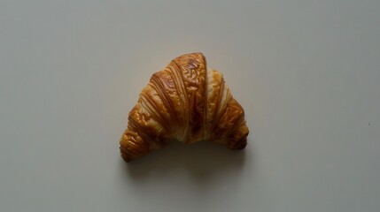   A croissant resting atop a table, with a nibble taken from it