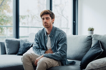 Sick young man in pain holding belly stomach feeling hurt abdomen ache gastritis pancreatitis symptoms or diarrhea, upset adult suffering from indigestion flatulence abdominal problem concept.