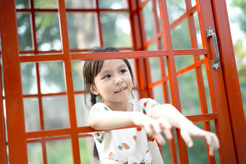 Little girl in a red phone booth. Emotional child talking on the phone. Soft focus. Copy space.