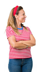 Beautiful middle age woman wearing casual stripes t-shirt over isolated background smiling looking to the side with arms crossed convinced and confident