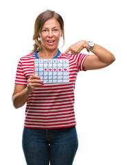 Middle age senior hispanic woman holding menstruation calendar over isolated background with surprise face pointing finger to himself