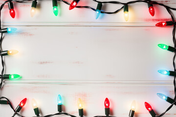 festive multicolored christmas lights on white wooden background