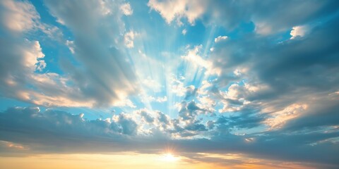 Fototapeta premium This image captures the mesmerizing view of sun rays breaking through scattered clouds in a serene blue sky, depicting the beauty and tranquility of nature at dawn.