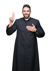 Young Christian priest over isolated background Swearing with hand on chest and fingers, making a...
