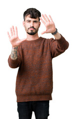 Young handsome man wearing winter sweater over isolated background Smiling doing frame using hands palms and fingers, camera perspective